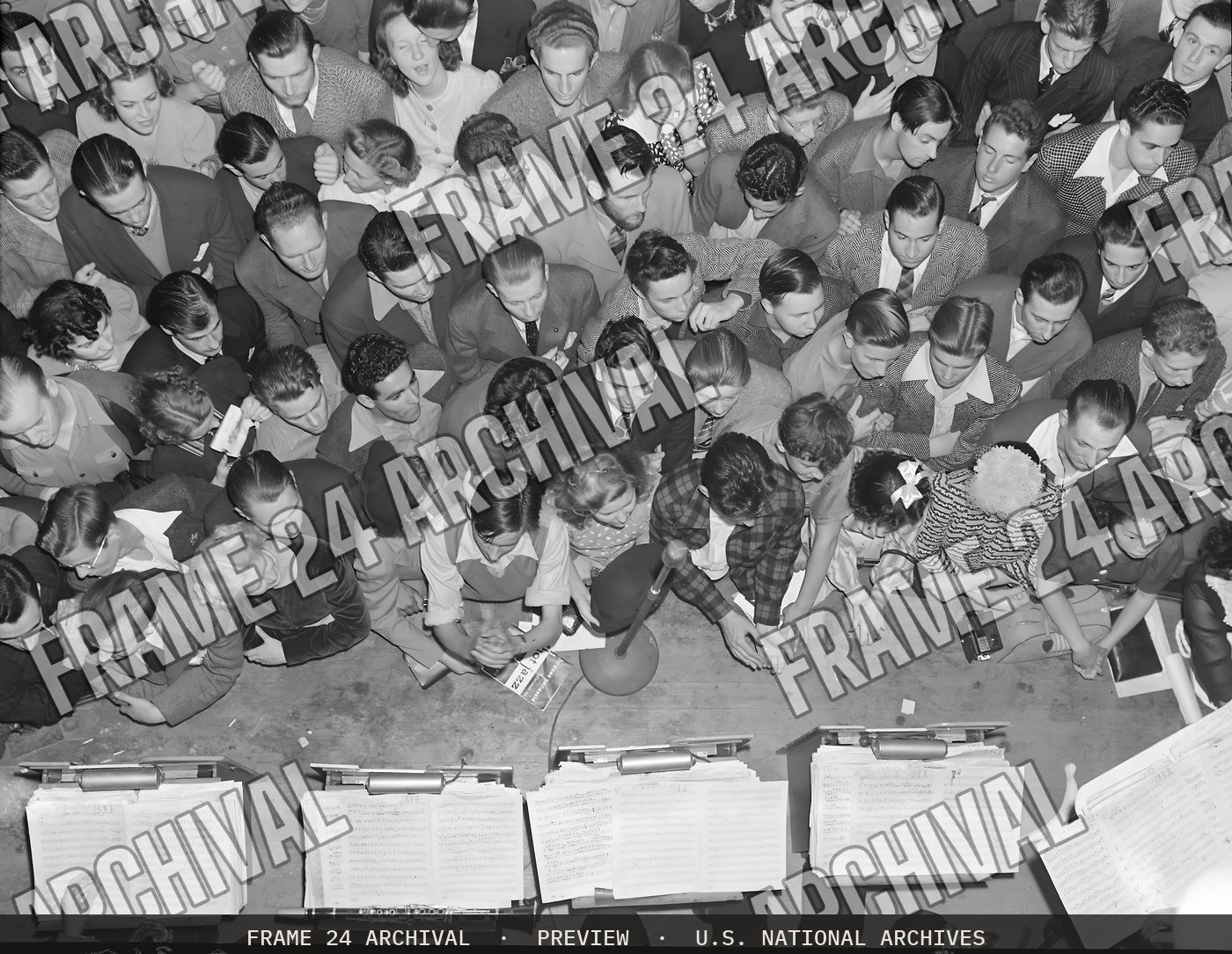 Oakland, California. Hot Jazz Recreation. Swing enthusiasts crowd against the band stand at an appearance of the Benny Googman Band in a local dance hall. One of the boys in the foreground has a copy (1940), restored vintage black and white photograph